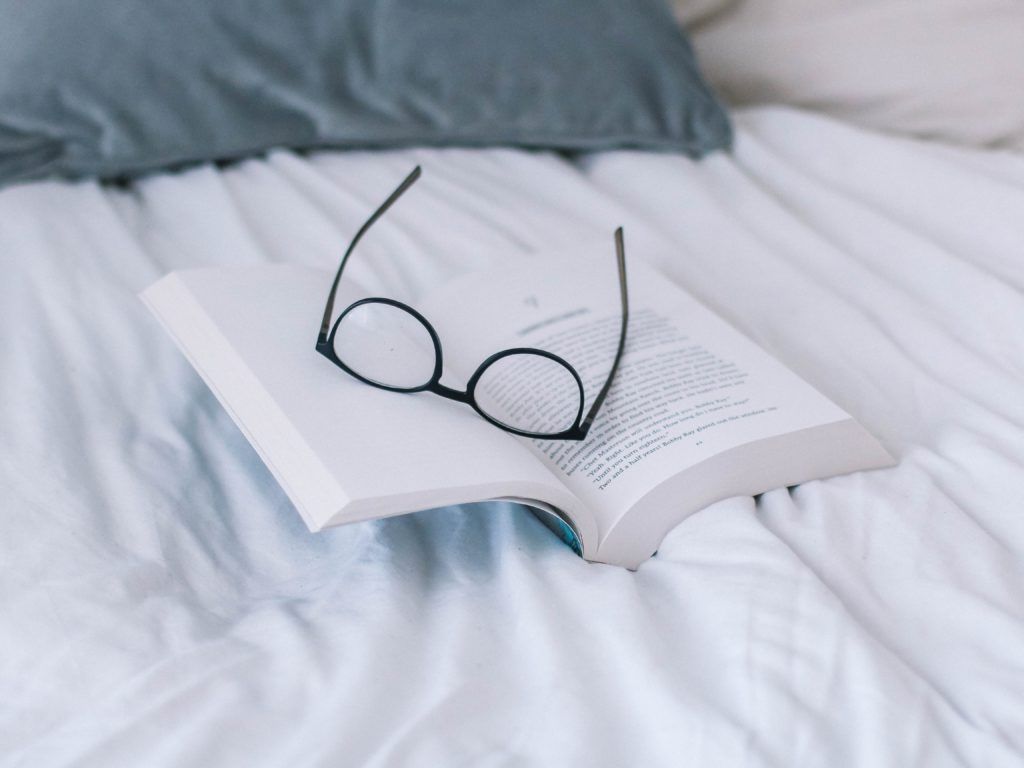 book on bed with glasses - how to read more
